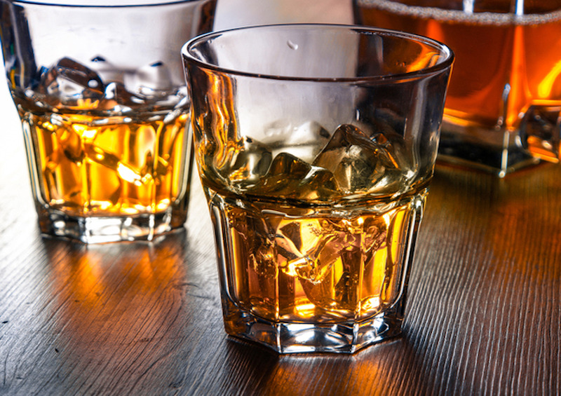 <p>Two glasses of whiskey on the rocks on a wooden table</p>