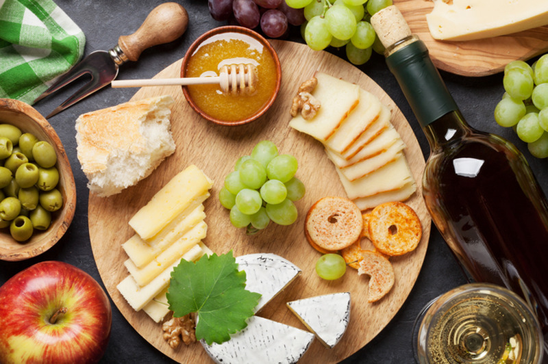 White wine, grape, bread, cheese plate and honey on stone table. Top view