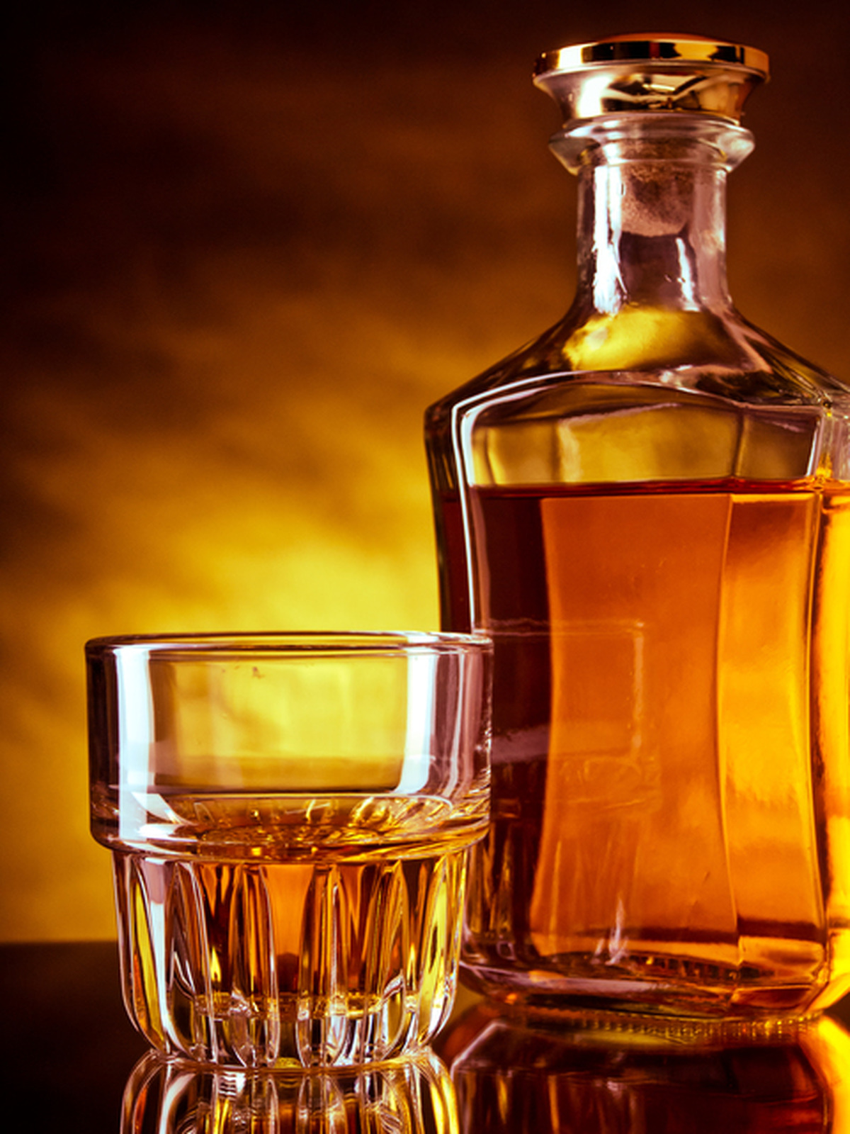 <p>Glass and a bottle of whisky against red and yellow background</p>