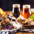 Roasted christmas duck leg red cabbage dumplings liver draft beer and baked buns.