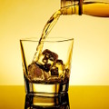 barman pouring whiskey in the glass on table with reflection, warm tint atmosphere