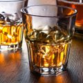 <p>Two glasses of whiskey on the rocks on a wooden table</p>