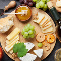 White wine, grape, bread, cheese plate and honey on stone table. Top view