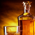 <p>Glass and a bottle of whisky against red and yellow background</p>