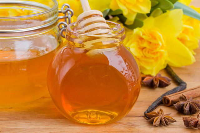glass jar of floral honey on wooden table